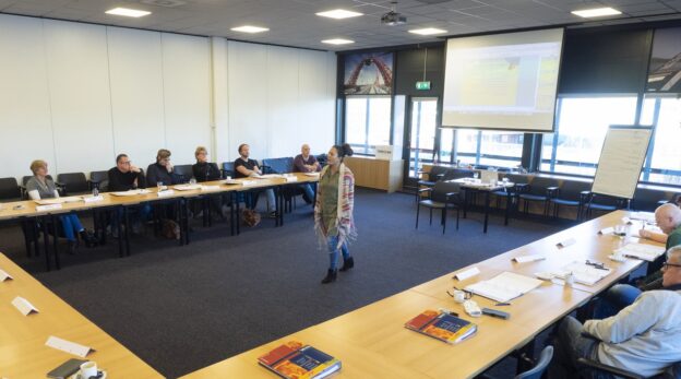 Docent aan het woord tijdens de cursus 'Pedagogisch Conciërge 1', terwijl deelnemers aandachtig luisteren